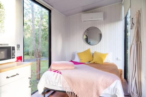 沃洛比Kawal Tiny House的一间卧室配有一张带黄色和粉红色枕头的床