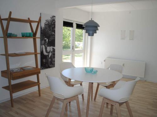 斯瓦讷克4 person holiday home in Svaneke的一间设有白色桌子和白色椅子的用餐室