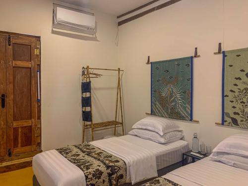 日惹Yukke Tembi Homestay的一间卧室设有两张床、一个窗口和一扇门