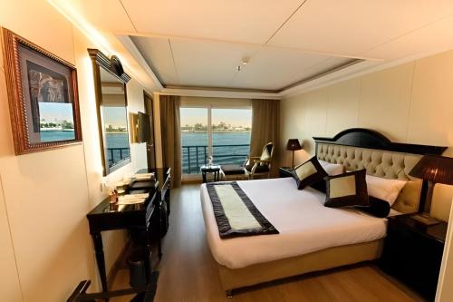 卢克索Super Nile Cruise LUXOR & ASWAN的配有一张床、一张书桌和一扇窗户的酒店客房