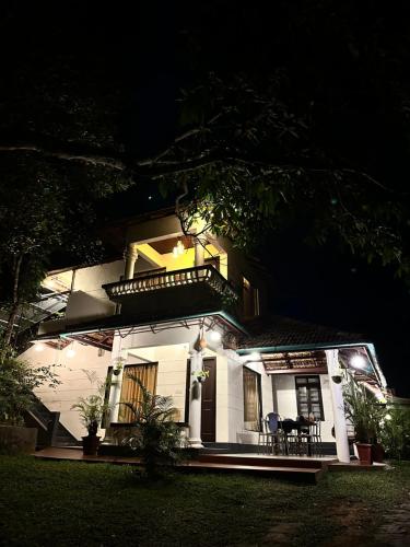 蒙纳Thoppil Homestay Munnar的白色房子,晚上设有阳台