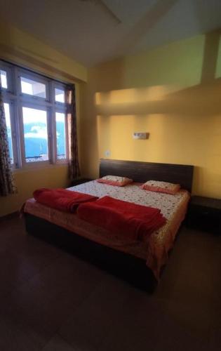 乌提Hotel Hill Valley, Ooty的一间卧室配有一张带红色床单的床和一扇窗户。
