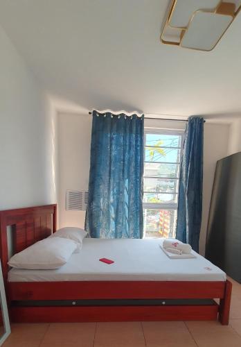 RomblonDRA Guesthouse的一间卧室配有一张带蓝色窗帘的床和窗户