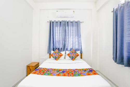 纳西克FabHotel Blue Ocean MNJ Resort的一间小卧室,配有一张带蓝色窗帘的床