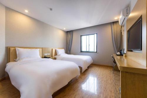 上海Hanting Hotel Shanghai Waitan Jiujiang Road的酒店客房设有两张床和一台平面电视。