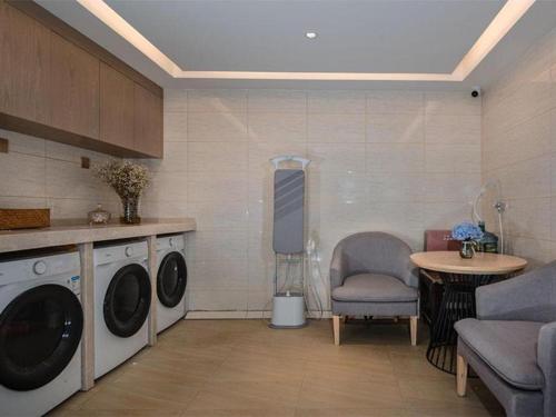 昆明Vienna Hotel Kunming Dashanghui的洗衣房配有洗衣机、桌子和椅子