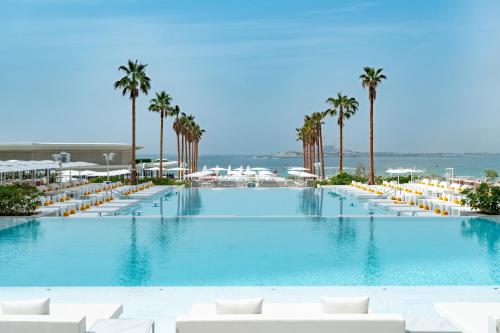 迪拜FIVE LUXE的一座带白色椅子和棕榈树的大型游泳池