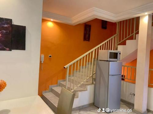 科托努RÉSIDENCES ORI的客房设有楼梯,冰箱内配有微波炉