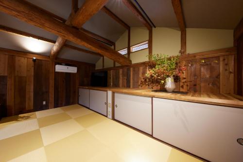 丰冈市ゲストハウス長閑的一间设有白色橱柜和木墙的大厨房