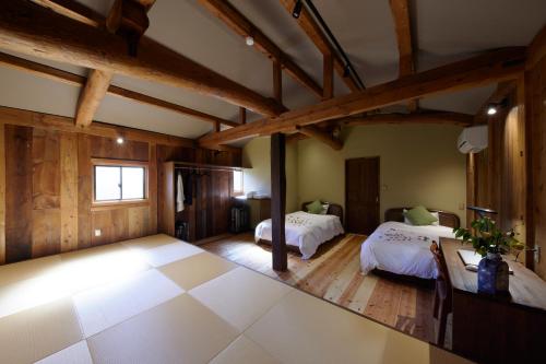 丰冈市ゲストハウス長閑的大房间设有两张床和木制天花板