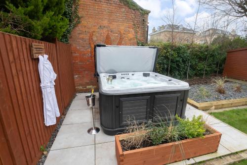 切尔滕纳姆Elliot Oliver - Superior 6 Bedroom House in Cheltenham With Hot Tub & Log Burner的浴缸位于围栏旁的花园内