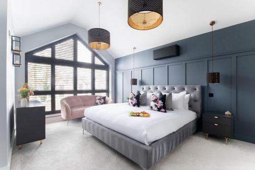 切尔滕纳姆Elliot Oliver - Superior 6 Bedroom House in Cheltenham With Hot Tub & Log Burner的一间卧室配有一张大床和一张粉红色的椅子