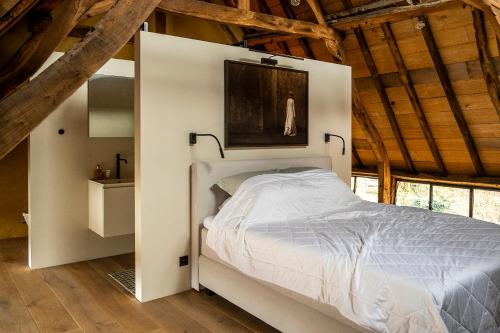 圣特雷登Sint-Truiden, Gootstraat 11的一间带白色床铺的卧室,位于带木制天花板的客房内。