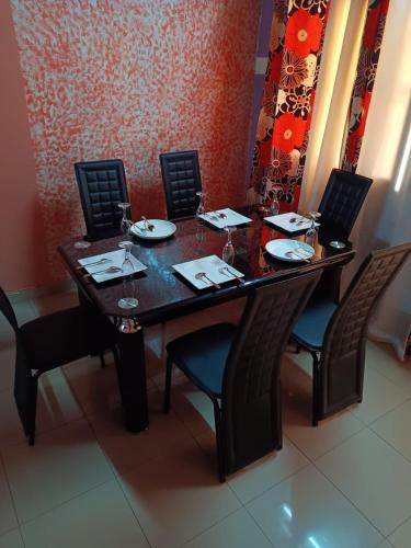 博博迪乌拉Résidence privée的一张木桌,配有椅子和盘子,酒杯