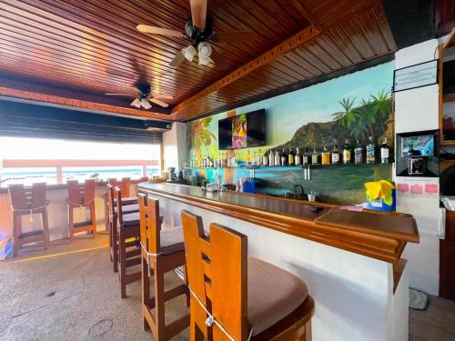 波尔多·格尼拉Montani Beach Resort Puerto Galera powered by Cocotel的酒吧配有椅子,墙上挂有绘画作品