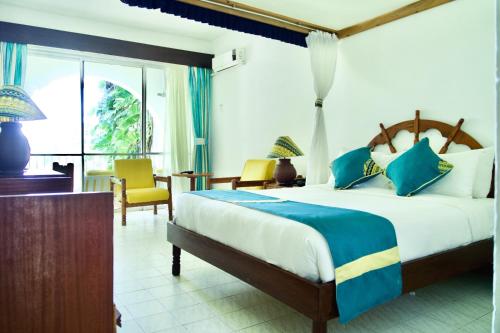 班布里普拉萨海滩酒店的一间卧室配有一张大床和一张桌子及椅子