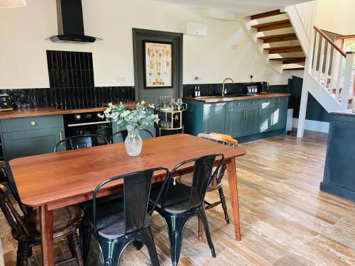 MattishallRayners Farm Lodge的厨房配有带椅子的木桌和花瓶