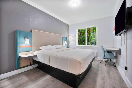 迈阿密Garden Hotel Miami Airport, Trademark Collection by Wyndham的一间卧室配有一张床、一张书桌和一个窗户。