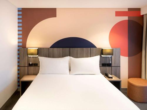 悉尼ibis Styles Sydney Central的一间卧室设有一张大床和一面墙