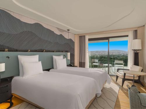 切什梅Swissotel Resort And Spa Cesme的一间带一张白色大床的卧室和一个阳台