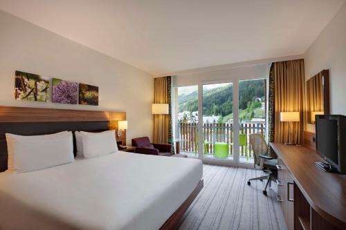 达沃斯达沃斯希尔顿花园酒店的酒店客房配有一张床和一张书桌及一台电视