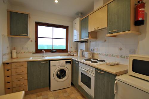 克雷尔Meadowshores Apartment Crail的厨房配有洗衣机和微波炉。