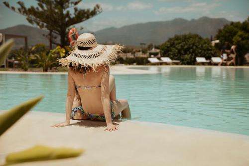 米哈斯La Zambra Resort GL, part of The Unbound Collection by Hyatt的坐在游泳池旁的戴帽子的女人