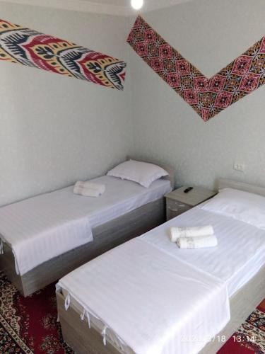 布哈拉Nur-Niso Guest House的小客房内的两张床,配有白色床单