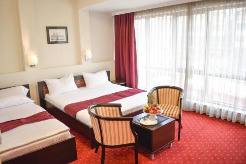 斯科普里Hotel Hamburg的酒店客房带两张床和一张桌子以及椅子。