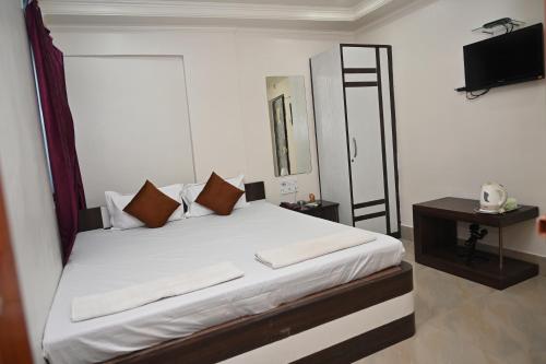 MāldahHOTEL GITANJALI的一间卧室配有一张带白色床单的床和电视。