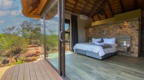 马布拉Shammah lodge Mabalingwe Nature Reserve的一间卧室设有一张床和一个大型玻璃窗