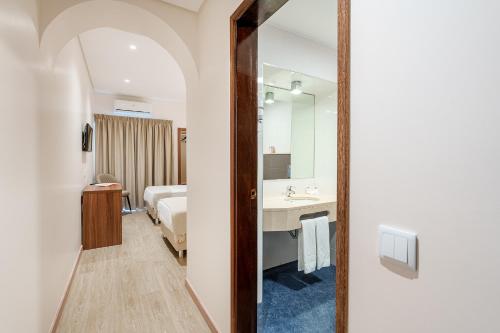 法蒂玛卡托利卡酒店的浴室设有床、水槽和镜子