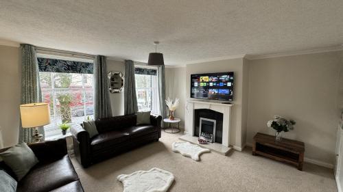 科克茅斯Hummingbird House的客厅配有黑色真皮沙发和壁炉