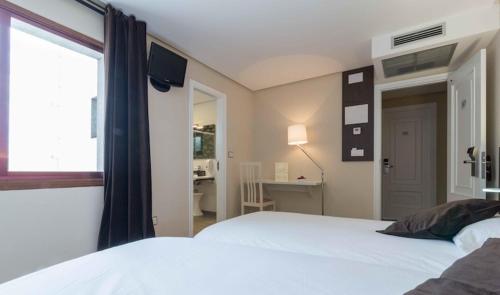 钱塔达莫伽依酒店的一间卧室配有一张床、一张书桌和一个窗户。