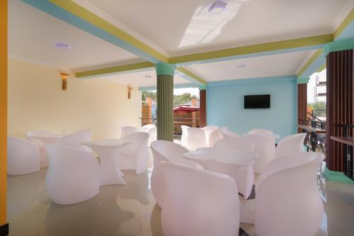 MbuguniNew Mazubu Grand Hotel Mererani的一间设有白色椅子和平面电视的客房