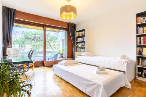 日内瓦Tourelle 2 - Spacieux appartement dans le centre de Genève的客房设有两张床、一张桌子和一扇窗户。