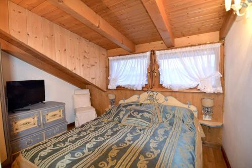 圣维托-迪卡多雷Cozy attic in the center of San Vito的小屋内一间卧室配有一张床和电视