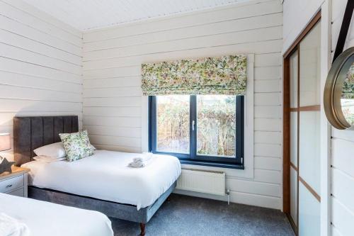 罗伊登Roydon Marina - Lodge 4 - Hot Tub的一间卧室设有两张床和窗户。