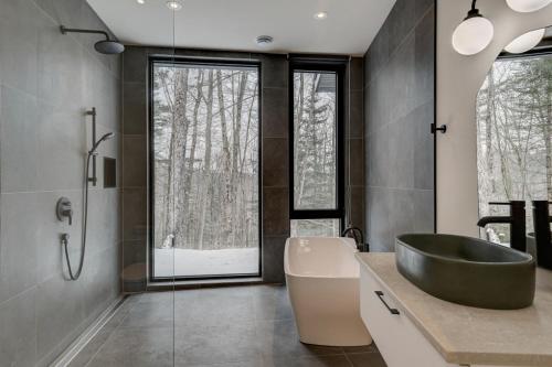 St-Etienne de BoltonAu Haut De La Colline Spa Et Sauna的浴室配有黑色浴缸、盥洗盆和浴缸。