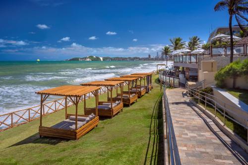 纳塔尔Serhs Natal Grand Hotel & Resort的海边沙滩上的一排床