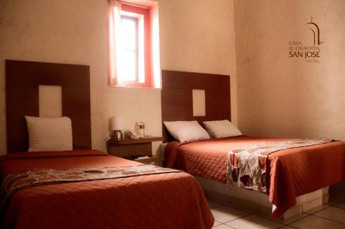 普埃布拉Hotel Casa de Oración San José的酒店客房设有两张床和窗户。