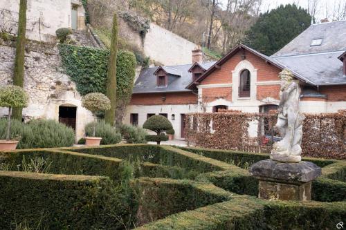 罗什科尔邦Manoir des Basses Rivières的房屋前带雕像的花园