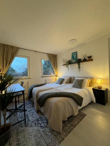 马尔默Central Peaceful Villa, Malmö的一间卧室设有两张床、一张桌子和两个窗户。