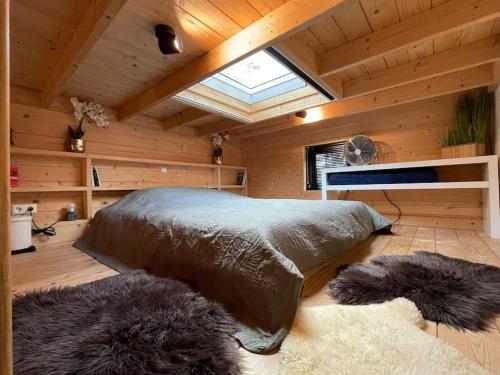 贝克贝亨Tiny House met Hottub op de Veluwe的木制客房内的一间卧室配有一张大床