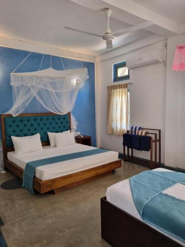 科斯戈德Darshana Beach Hotel的一间卧室设有两张床和蓝色的墙壁