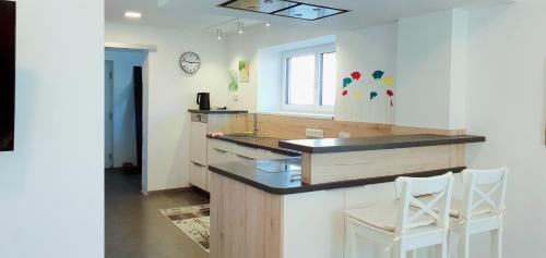 林茨3-Zimmer- Wohnung in Traun, nähe Linz und Wels的厨房配有柜台和2把白色椅子