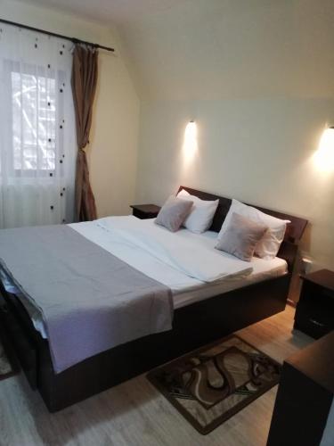 锡纳亚Casa Din Padure的卧室配有一张带白色床单和枕头的大床。