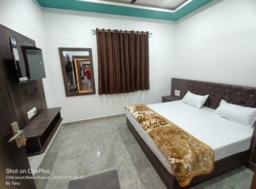 Sītāpur MūāfiHotel Parvati Residency的一间卧室配有一张床、镜子和电视