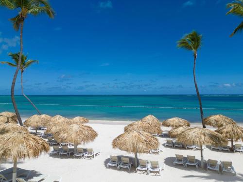 蓬塔卡纳Sunscape Coco Punta Cana - All Inclusive的海滩上的一把稻草遮阳伞和椅子