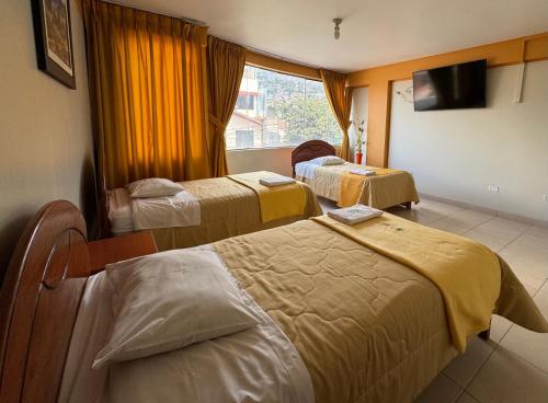 阿亚库乔Illari Wari l - Hotel Sauna的酒店客房设有三张床和窗户。